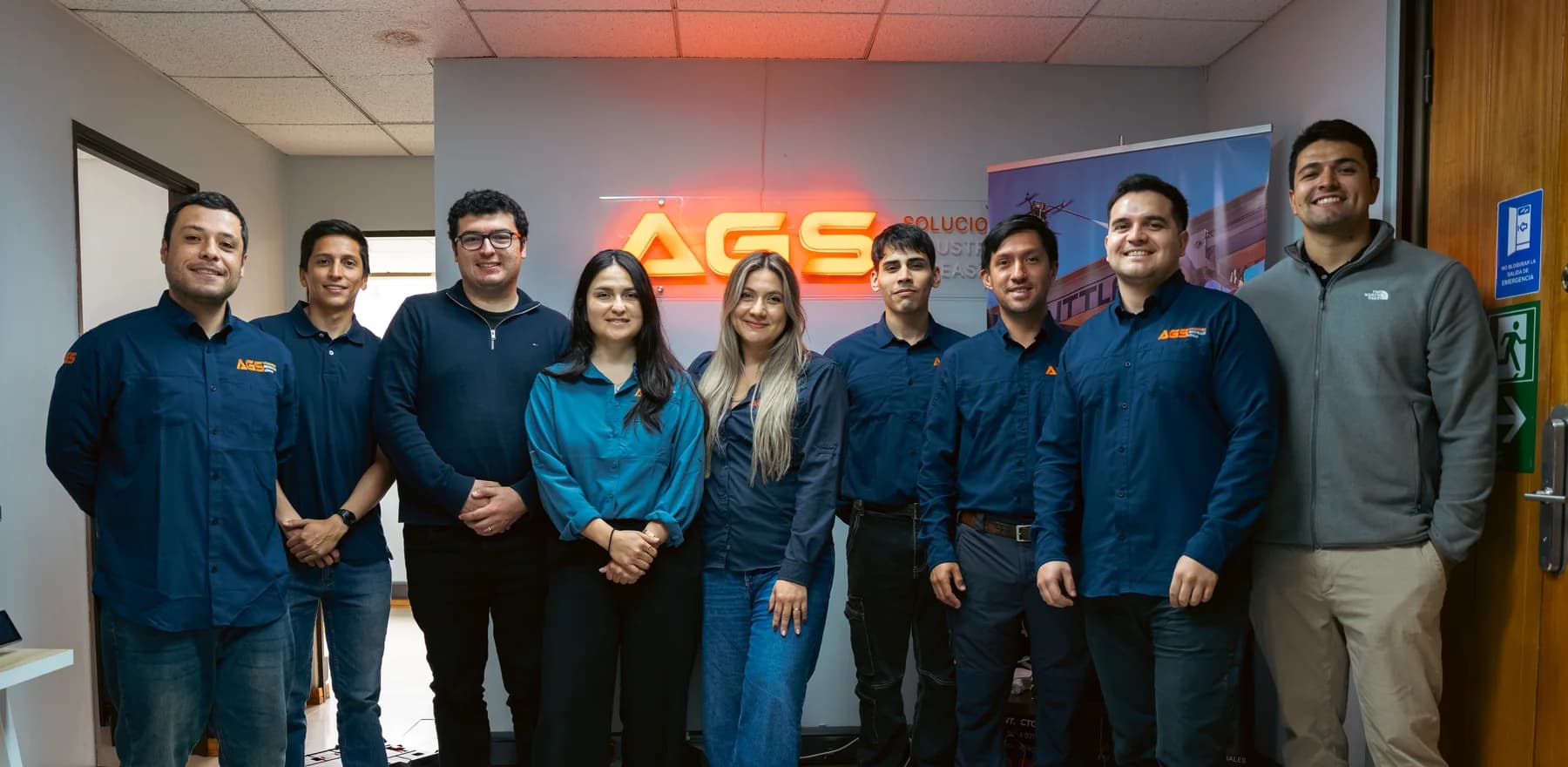 Equipo de AGS Soluciones reunido frente al letrero corporativo en sus oficinas
