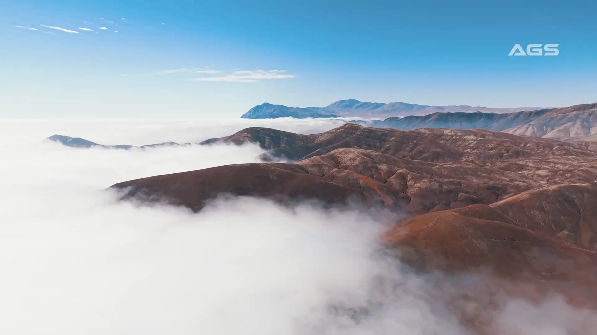 Vista aérea de cerros del desierto que emergen sobre un mar de nubes