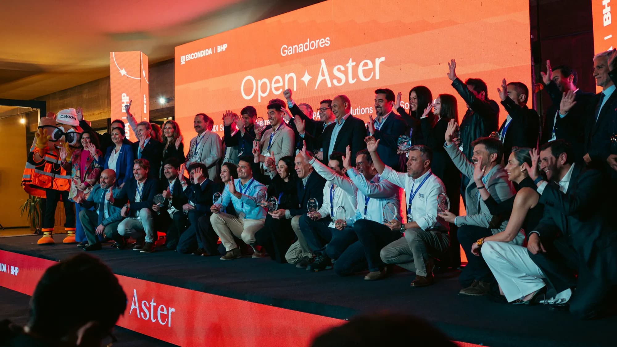 Las empresas seleccionadas en Open Aster sobre el escenario, con sus galvanos en la mano y la pantalla de Escondida | BHP de fondo